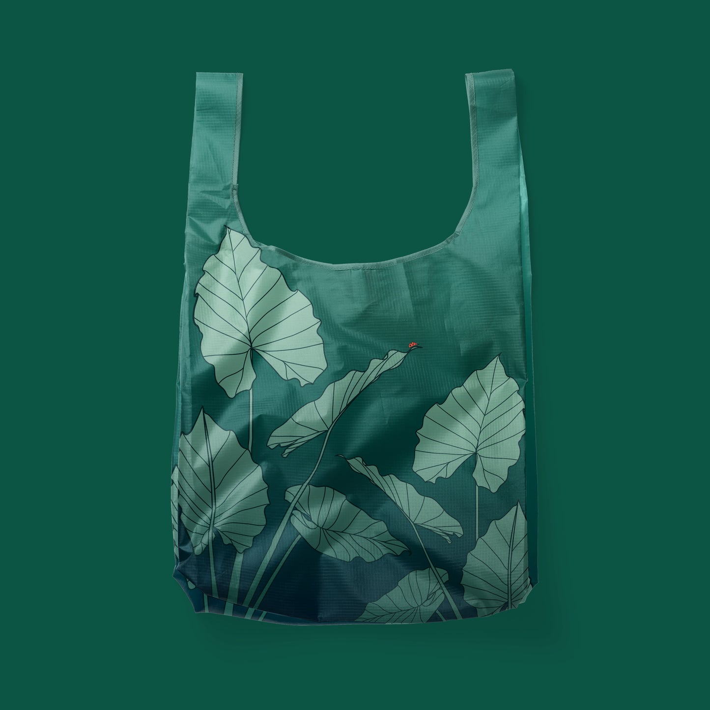 Green reusable tote, detailed with alocasia leaves and a red ladybug on the leaf.