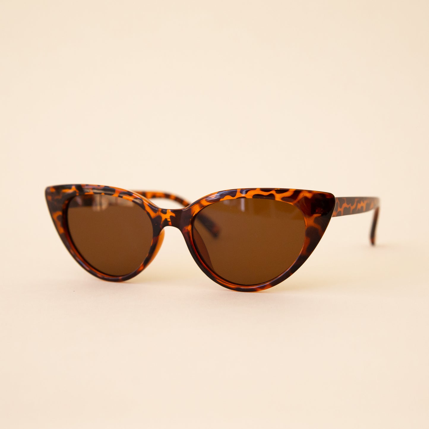 A brown tortoise print pair of cat-eye shaped sunglasses.