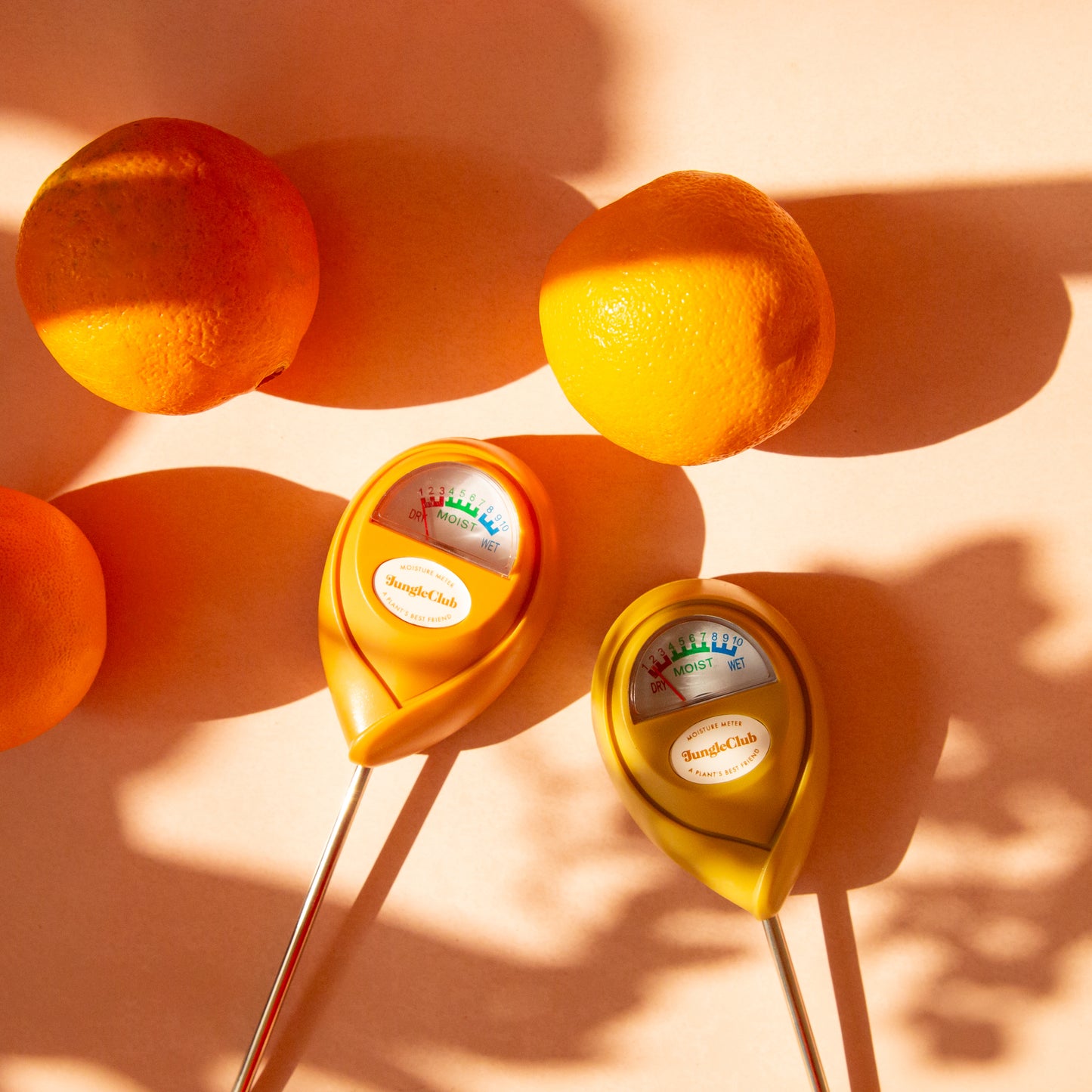 An orange moisture meter with a rounded head and a white meter that ranges from dry, moist, or wet along with a small oval label in the front that reads, "Jungle Club".