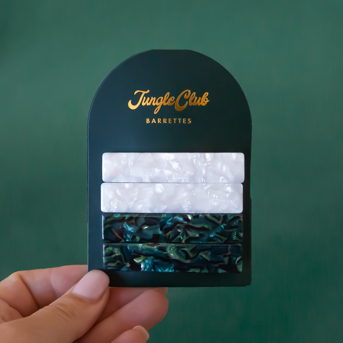 A set of four acetate barrettes in a green and white color.