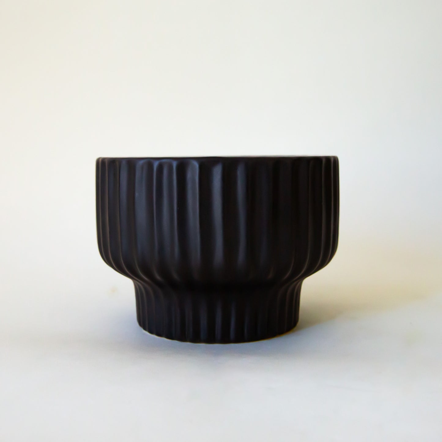 A ribbed black pedestal bowl planter.