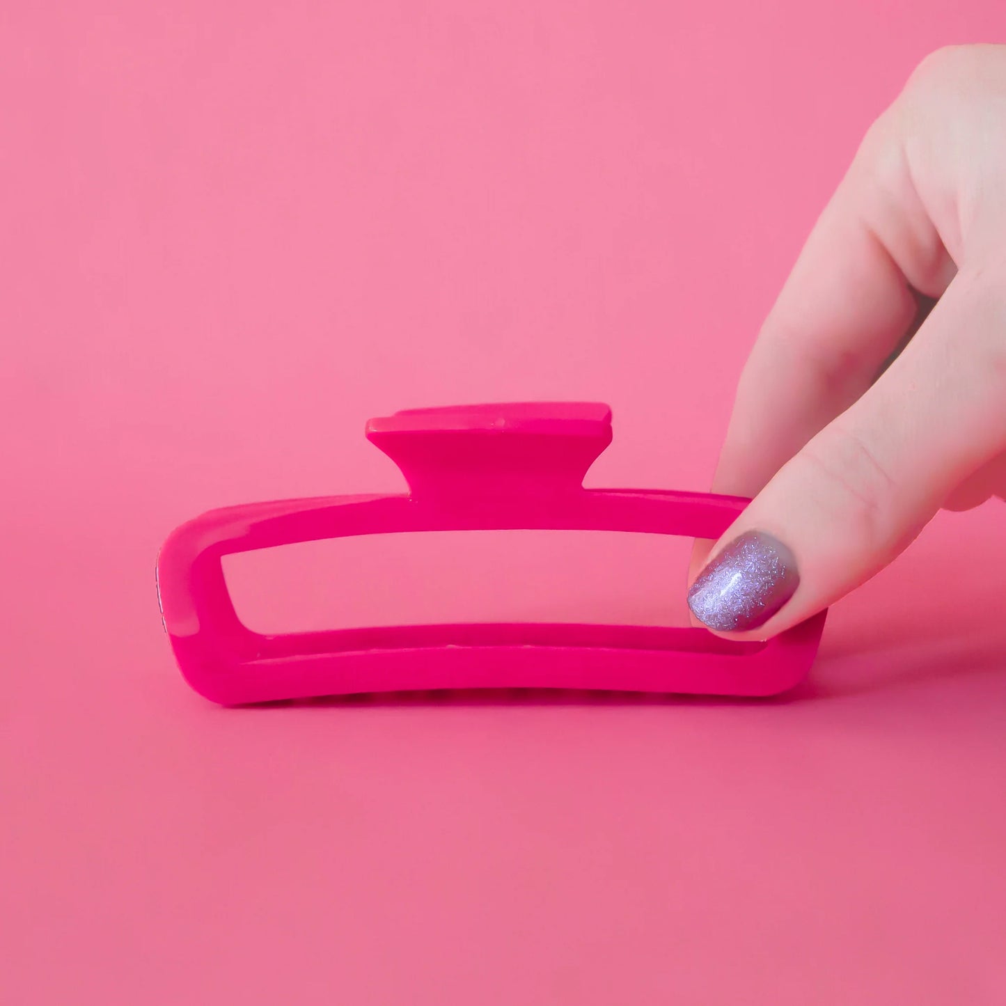 A hot pink rectangle claw clip with rounded edges.