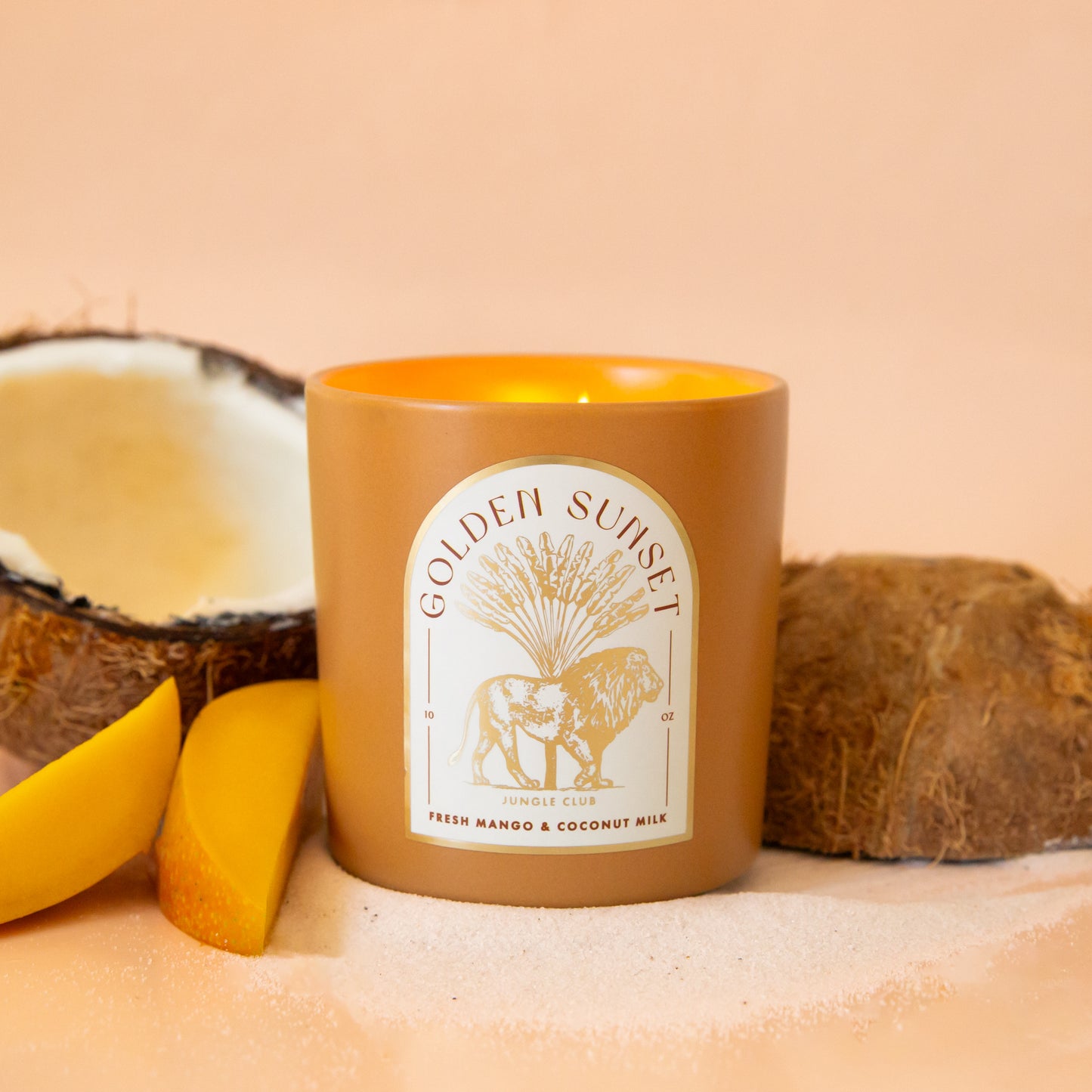 An orange candle with an arched label with a lion graphic and text above that reads, 'Golden Sunset'.