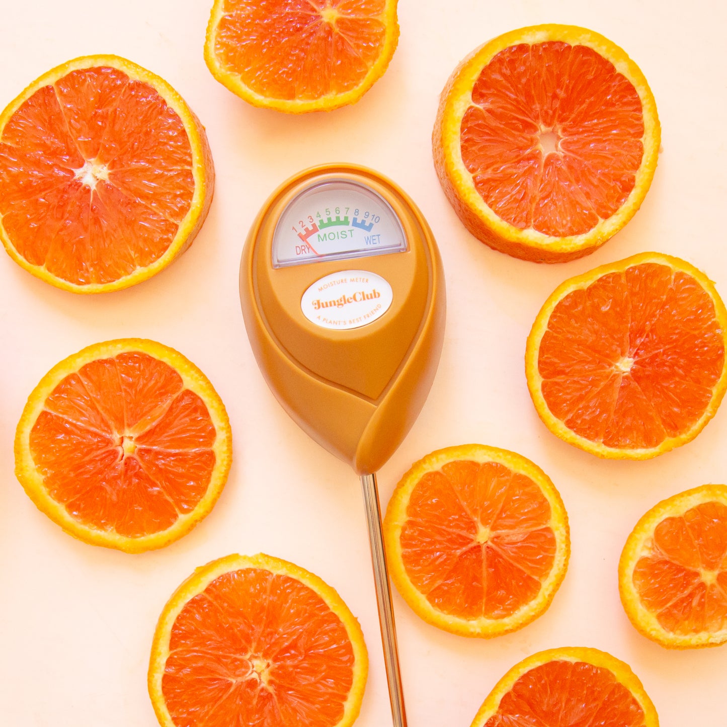 An orange moisture meter with a rounded head and a white meter that ranges from dry, moist, or wet along with a small oval label in the front that reads, "Jungle Club".