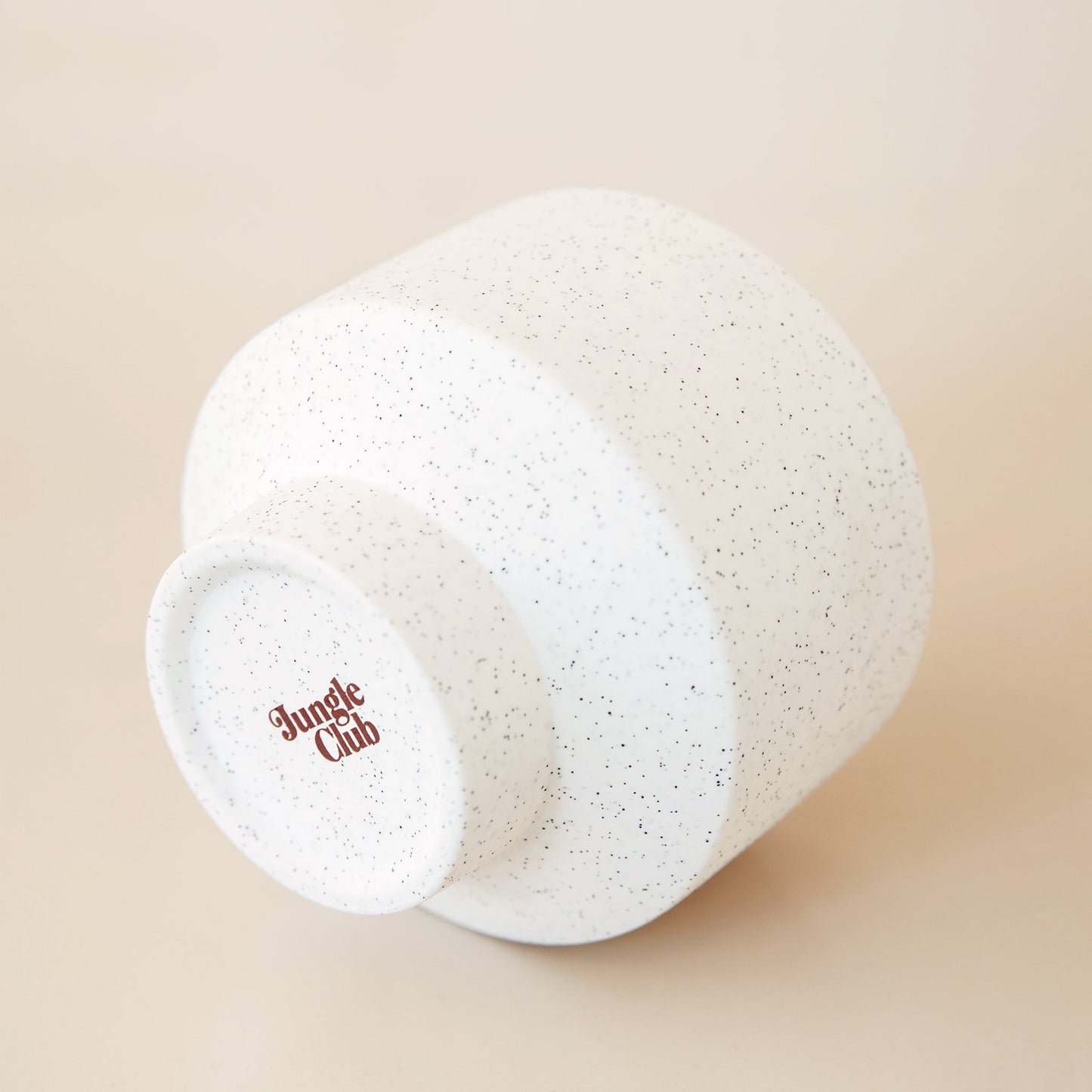 Bottom view of white speckled pot. The bottom of the pot reads 'jungle club' in a rust color.