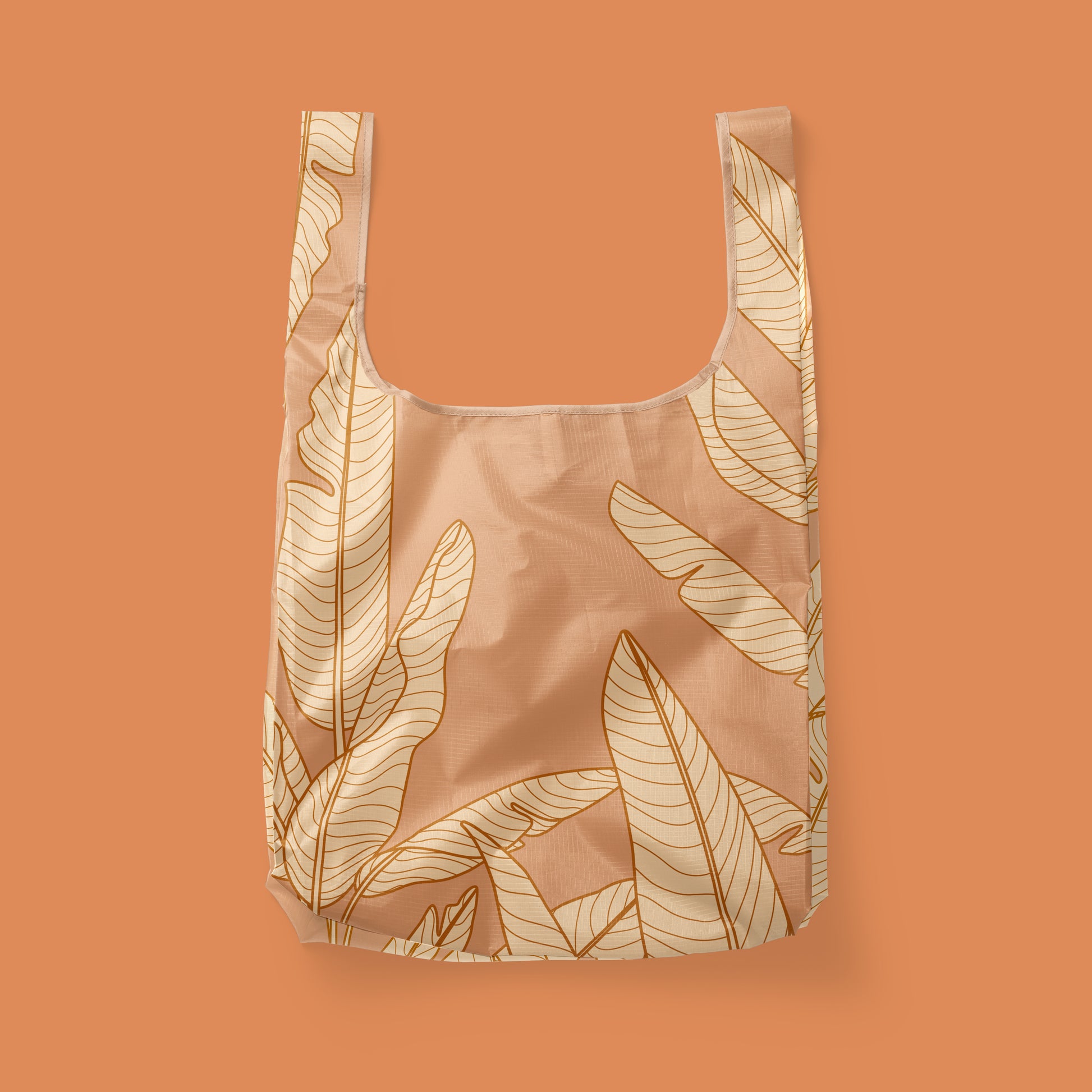 A light orange reusable nylon tote bag with a banana leaf pattern. 