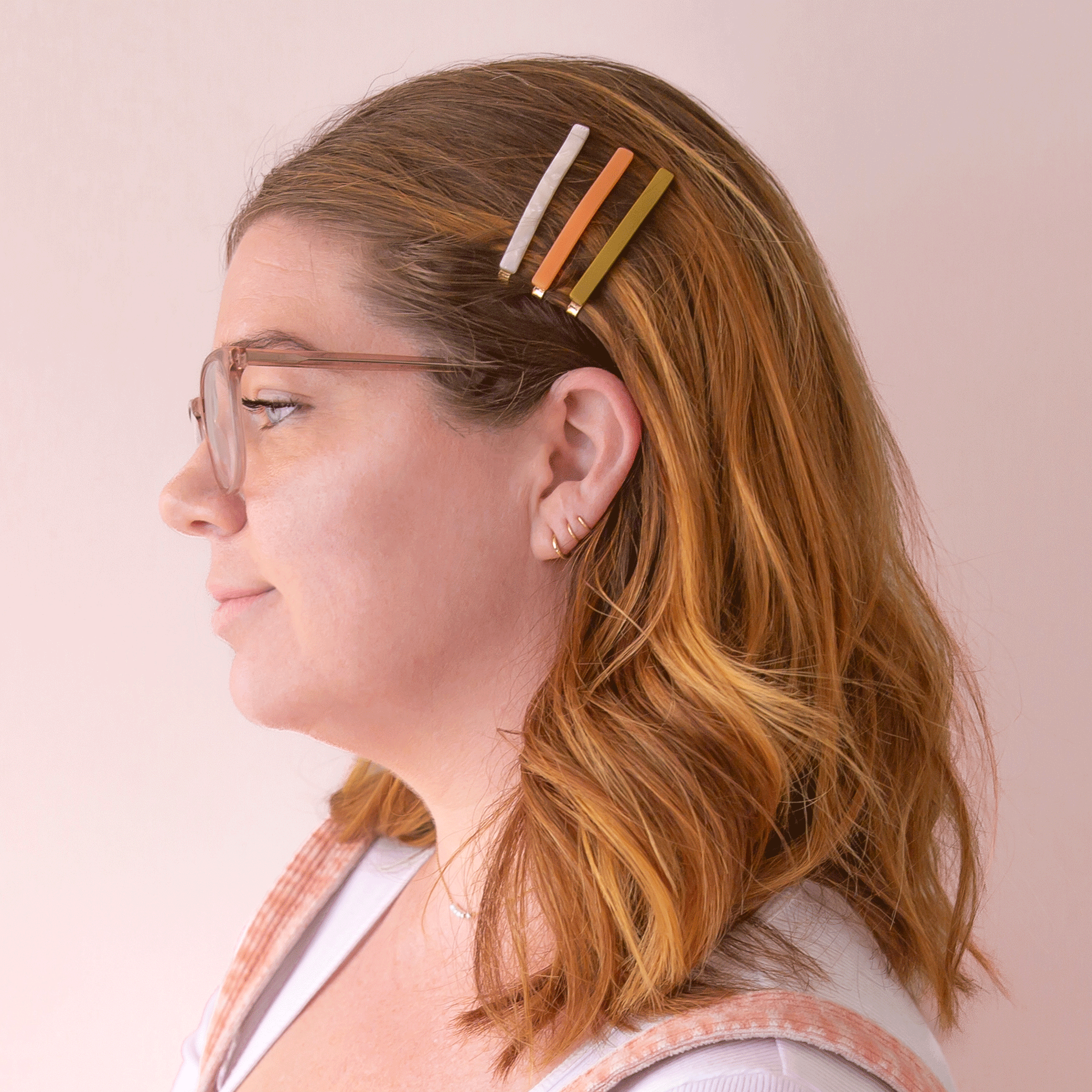 Three acetate bobby pins from top to bottom is an ivory shell shade, mango orange, and olive green shade.