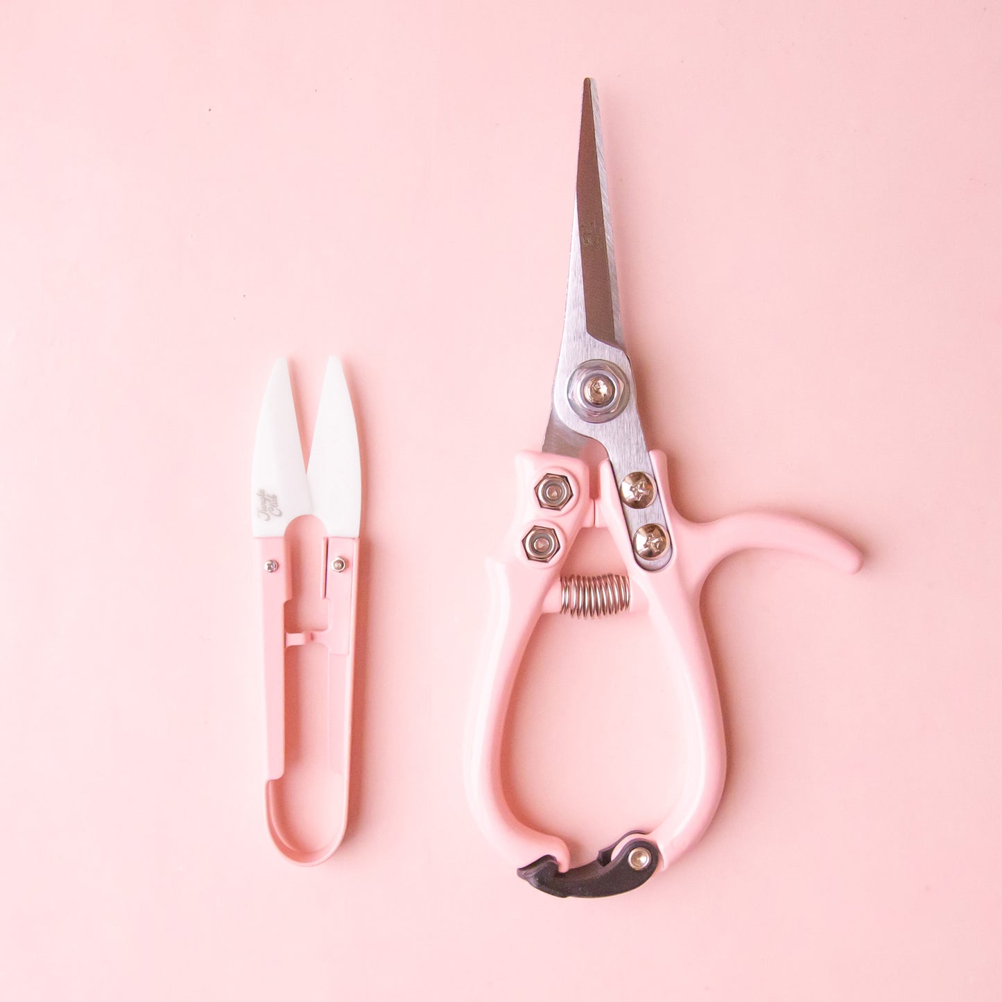 A pair of light pink pruning shears and mini plant snips. 