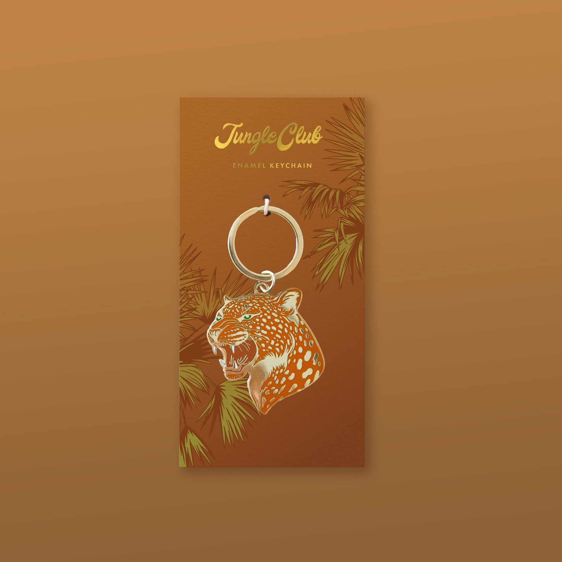 An orange leopard print enamel keychain on a keychain backer with leaf pattern.
