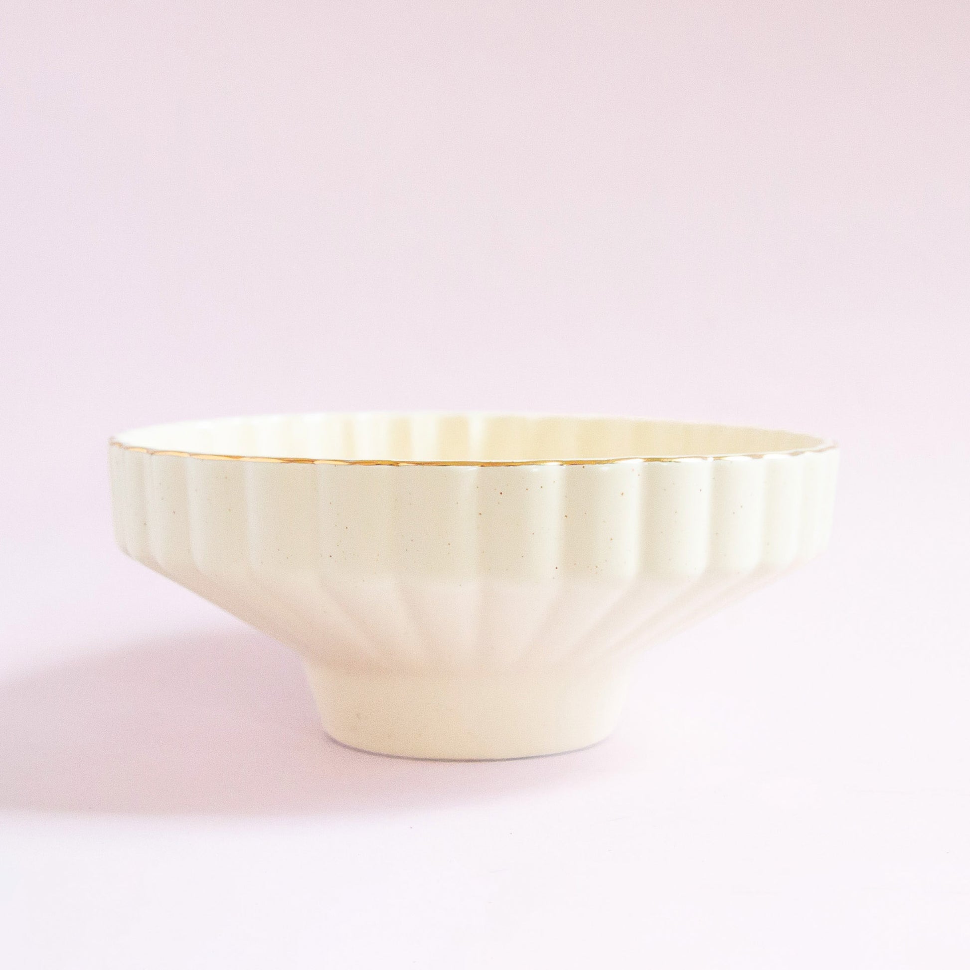 A scalloped ceramic pedestal bowl with a gold rim.

