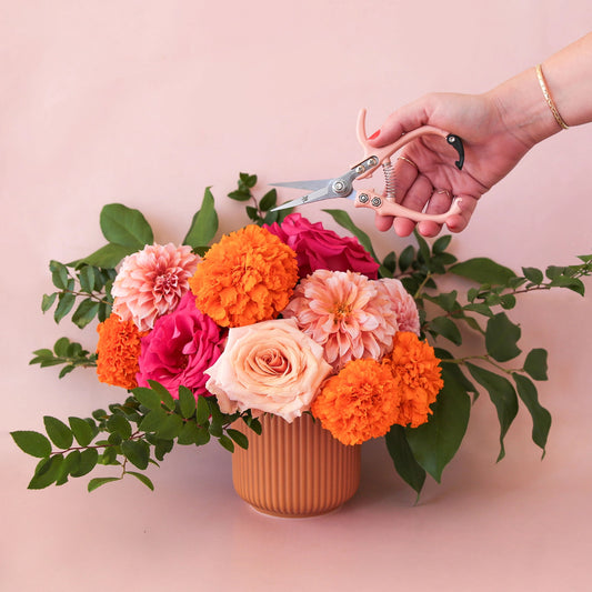 An orange ceramic planters with a fluted detail and a rounded base. 