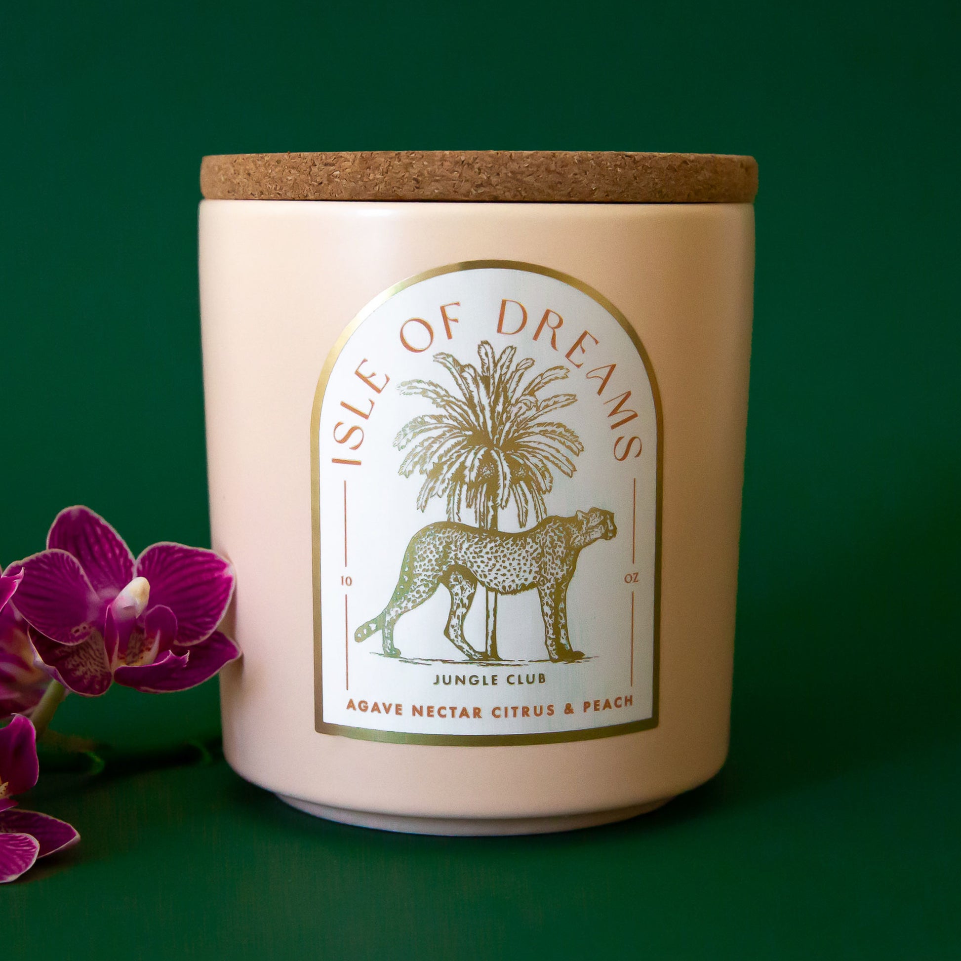 A neutral candle with an arched label with a cheetah and palm tree graphic and text that reads, 'Isle of Dreams'. 