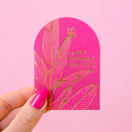 A hot pink arched card with gold foiled text that reads, 'Happy Birthday Beautiful'