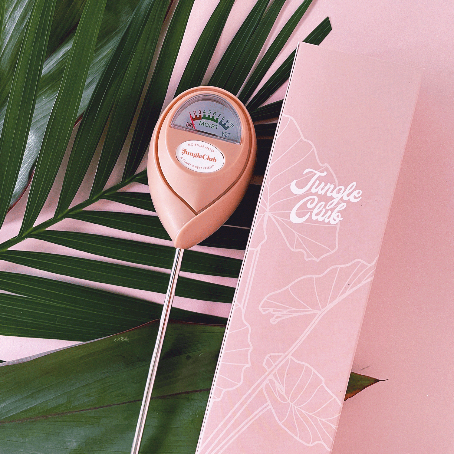 A pink moisture meter with a rounded head and a white meter that ranges from dry, moist, or wet along with a small oval label in the front that reads, "Jungle Club".