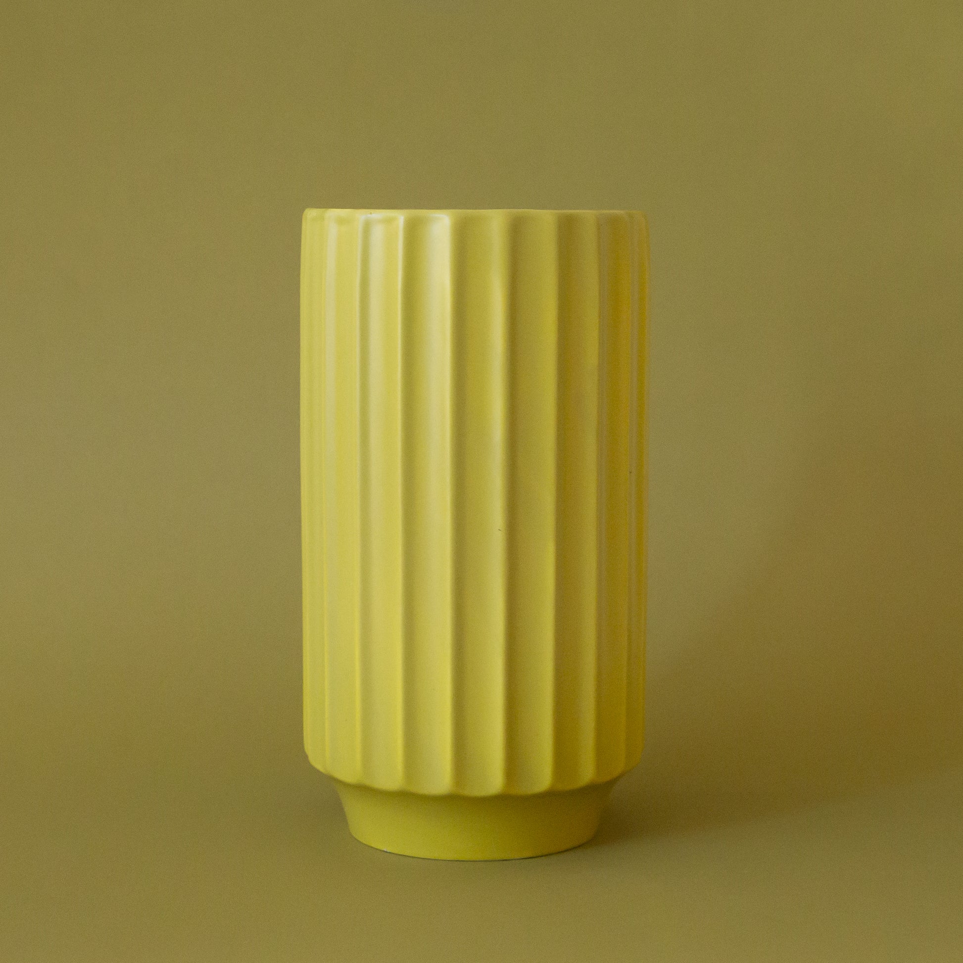 A beautiful chartreuse fluted cylindrical vase made our of a ceramic material. 