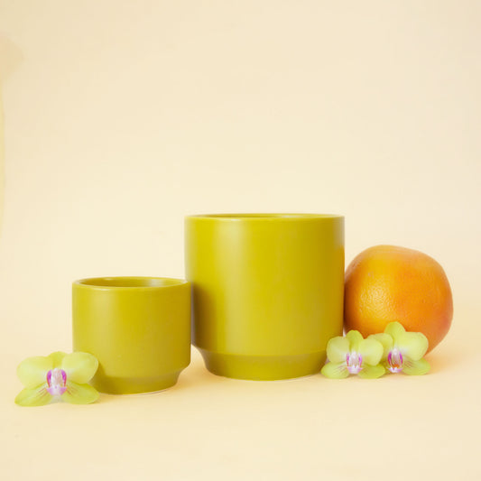 On an ivory background is three different sized ceramic planters in chartreuse shade with a slight speckle detail and a tapered base.