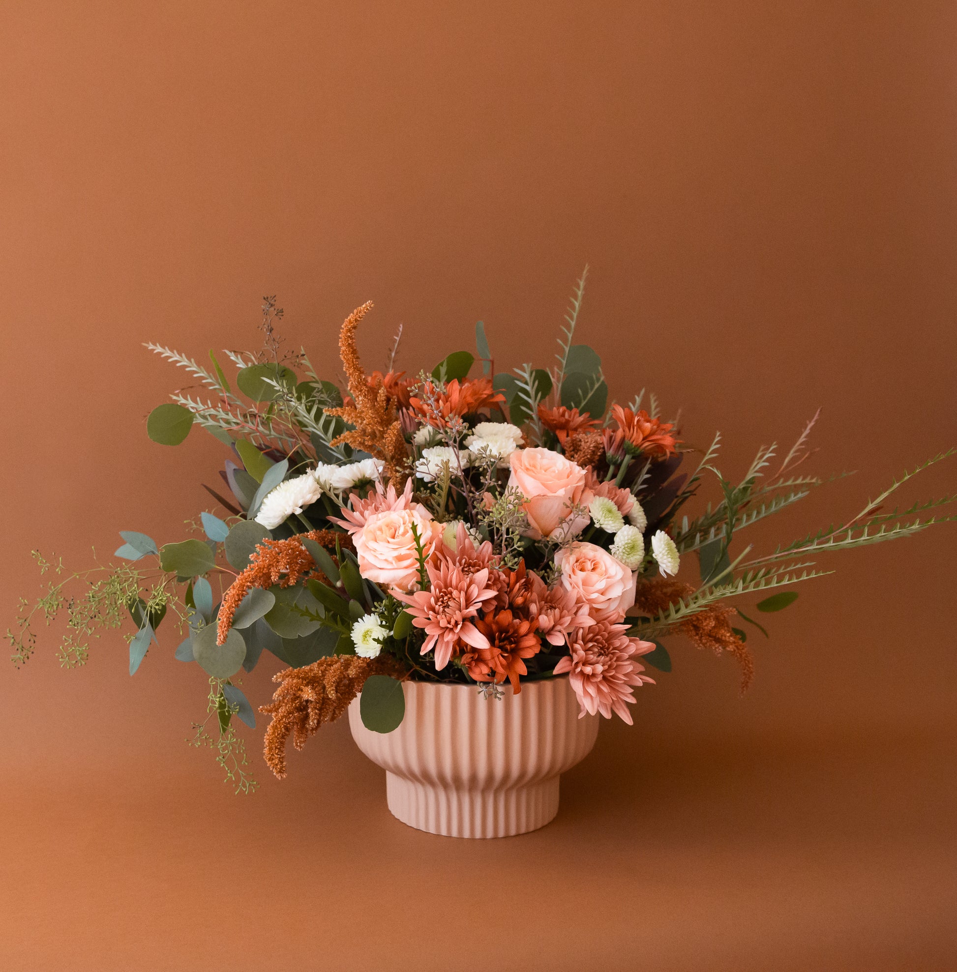 Three different sized tan / light orange ceramic pedestal planters with a ribbed texture. 