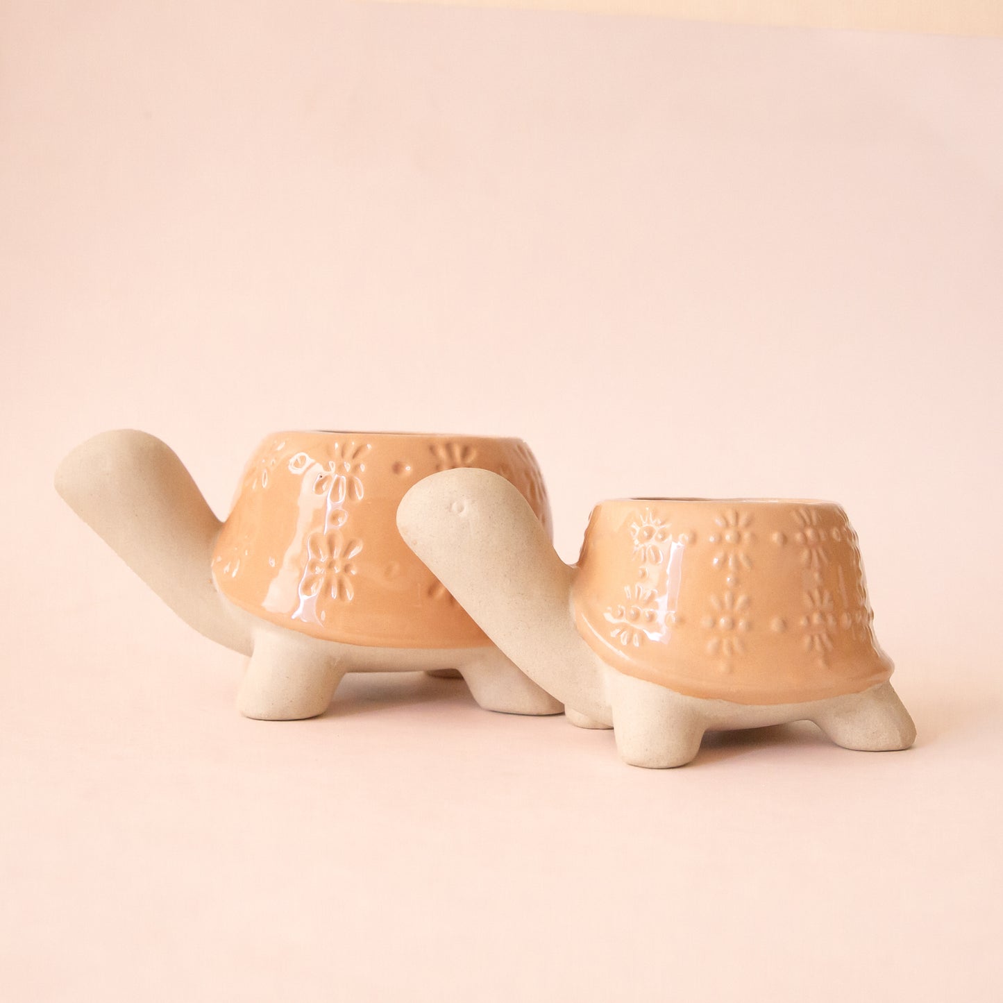 A set of two different sized ceramic turtle planters with a light orange "shell". 