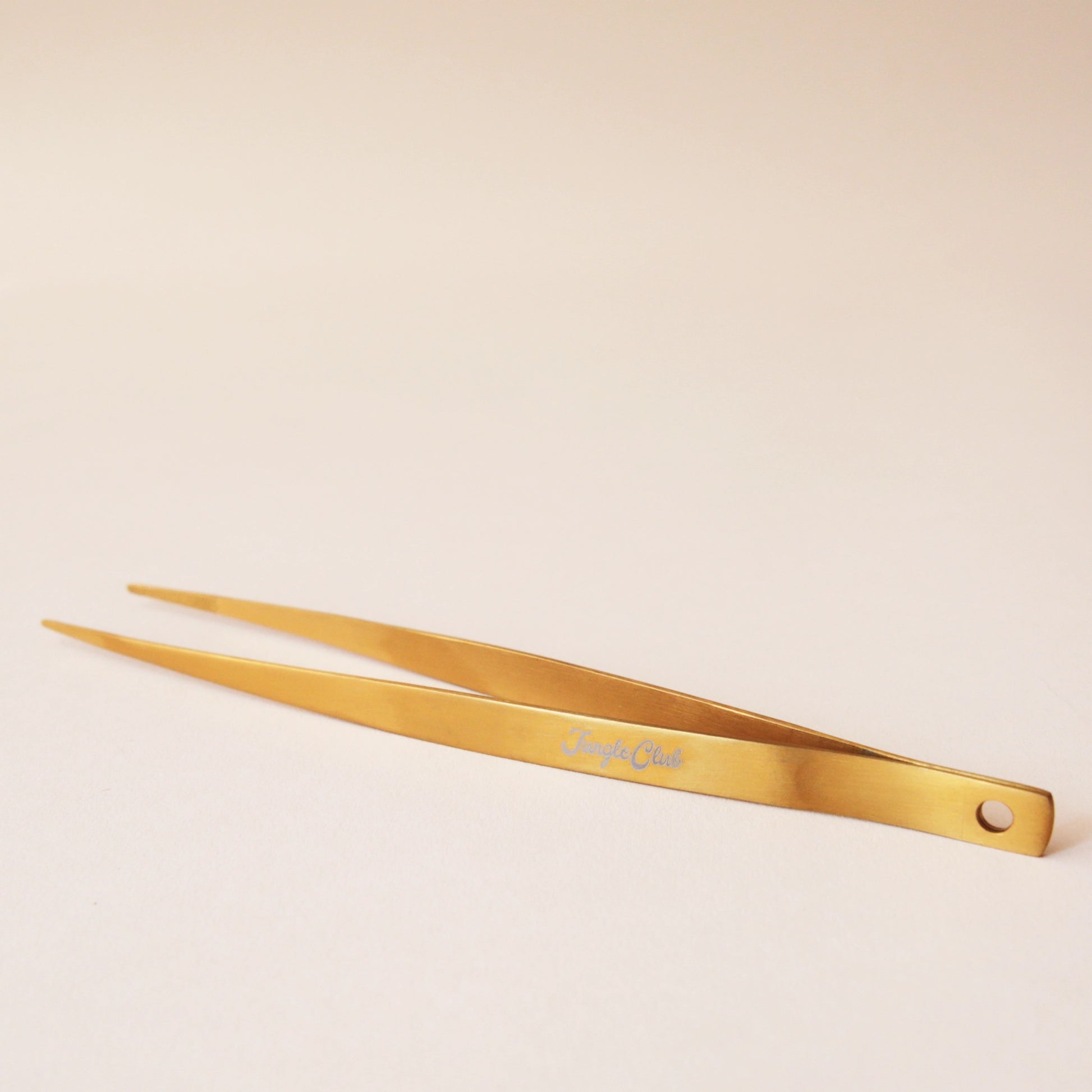 Brass tweezers with a slim design and a pointed tip perfect for handling spiky cacti. On the side of the tweezer there is text that reads, "Jungle Club" I white cursive.