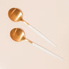 On a cream background is two brass planting spoons with a white handle that has a pointed end.