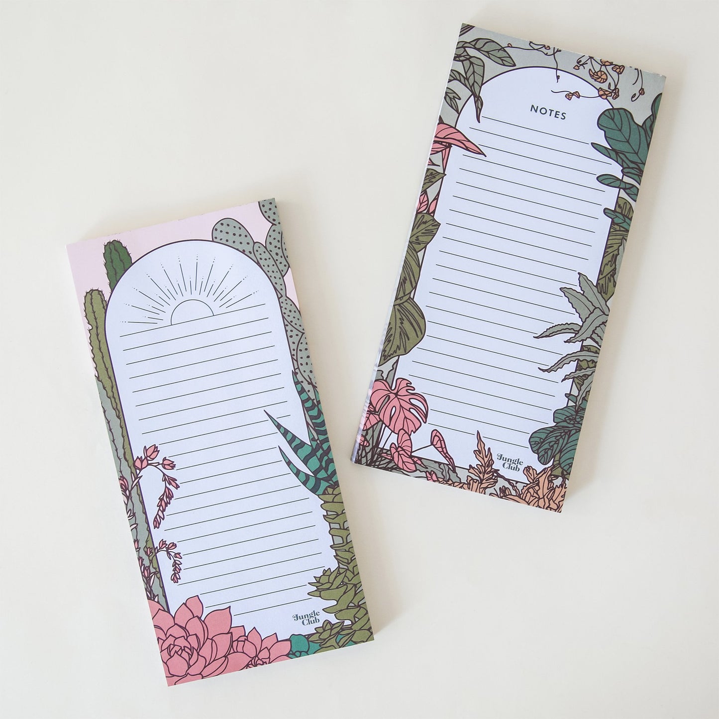 This weekly planner pad has a section for each day of the week with a deep green border, accented by an array of natural, soft toned jungle plants. Besides lays a rectangular notepad with the same design labeled 'Notes' and a baby pink ball point pen.