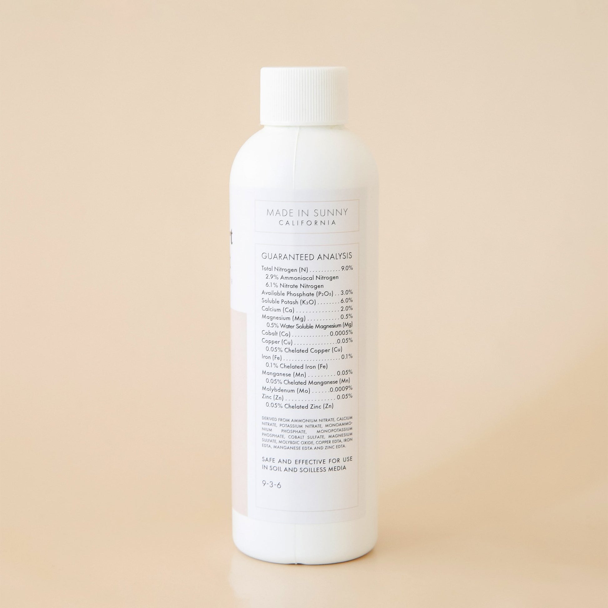 The back side of the bottle reads 'Made in Sunny California' in black capital lettering. Below is a detailed list of ingredients titled 'Guaranteed Analysis'. Both the title and ingredient lists are outlined in a thin, soft beige border.  Edit alt text
