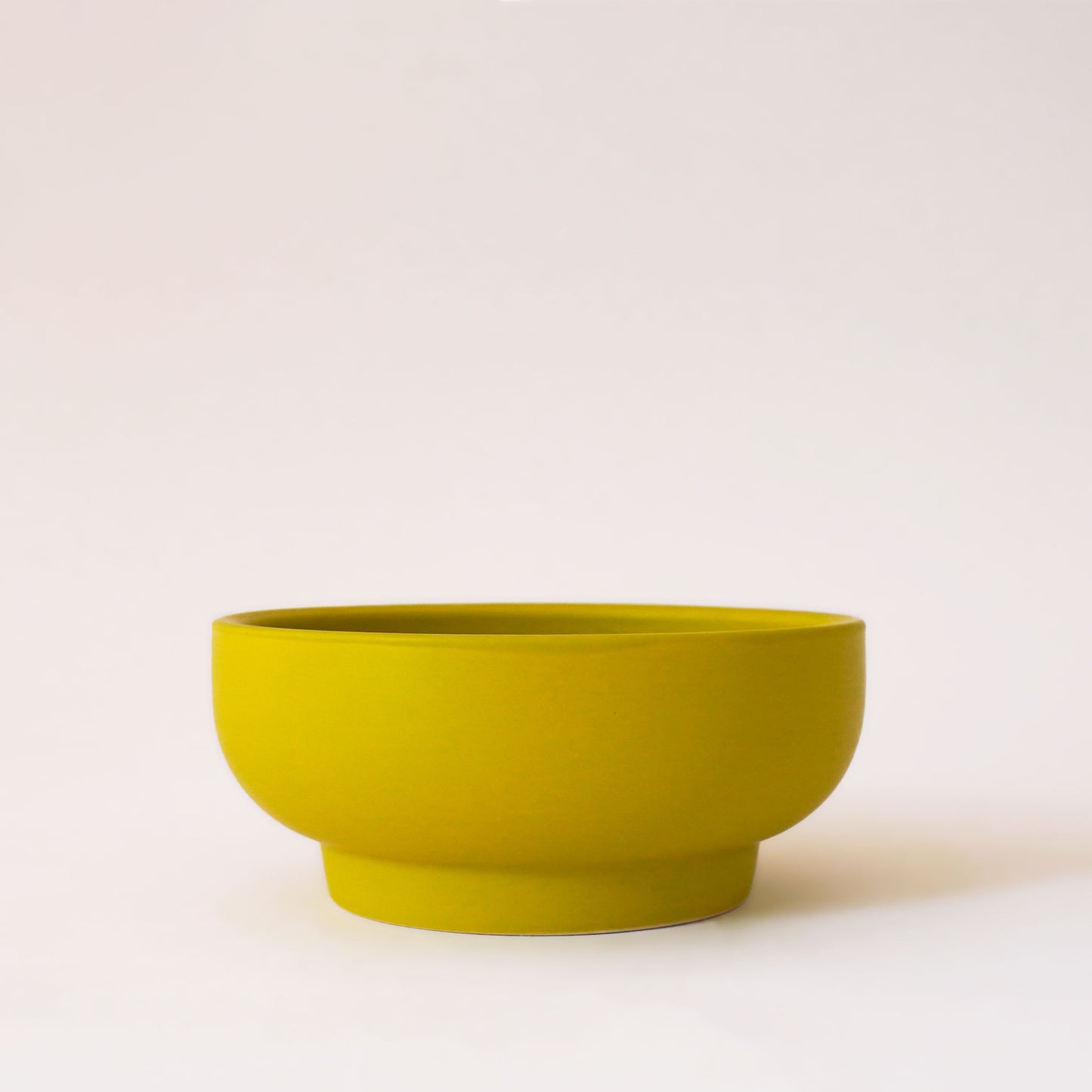 Chartreuse orange bowl planter that tapers towards the base.